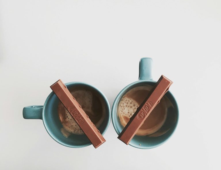 Two cups of coffee with kitkat bars on top