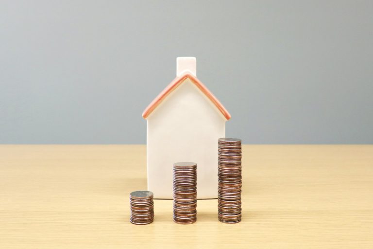 Model house with coins stacked in front