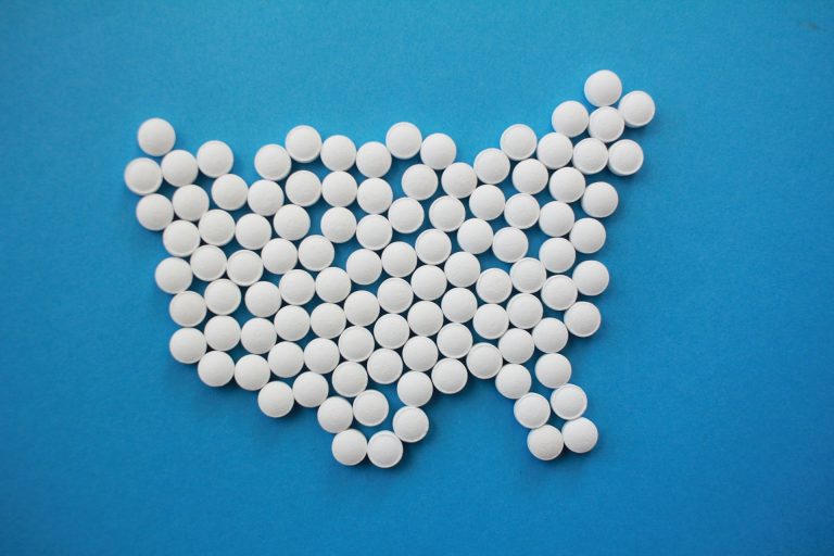 White pills placed in the shape of the USA on a blue background