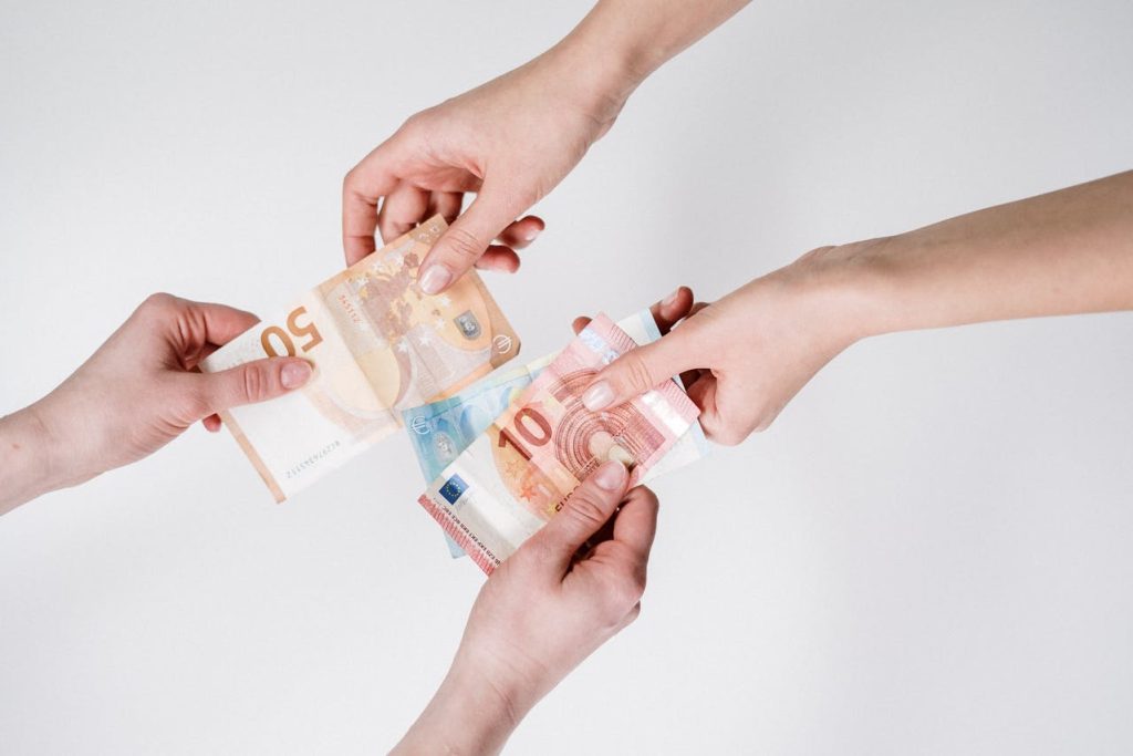 Two pairs of hands exchanging money (euros)