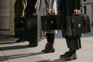 Four people with briefcases standing in a straight horizontal line