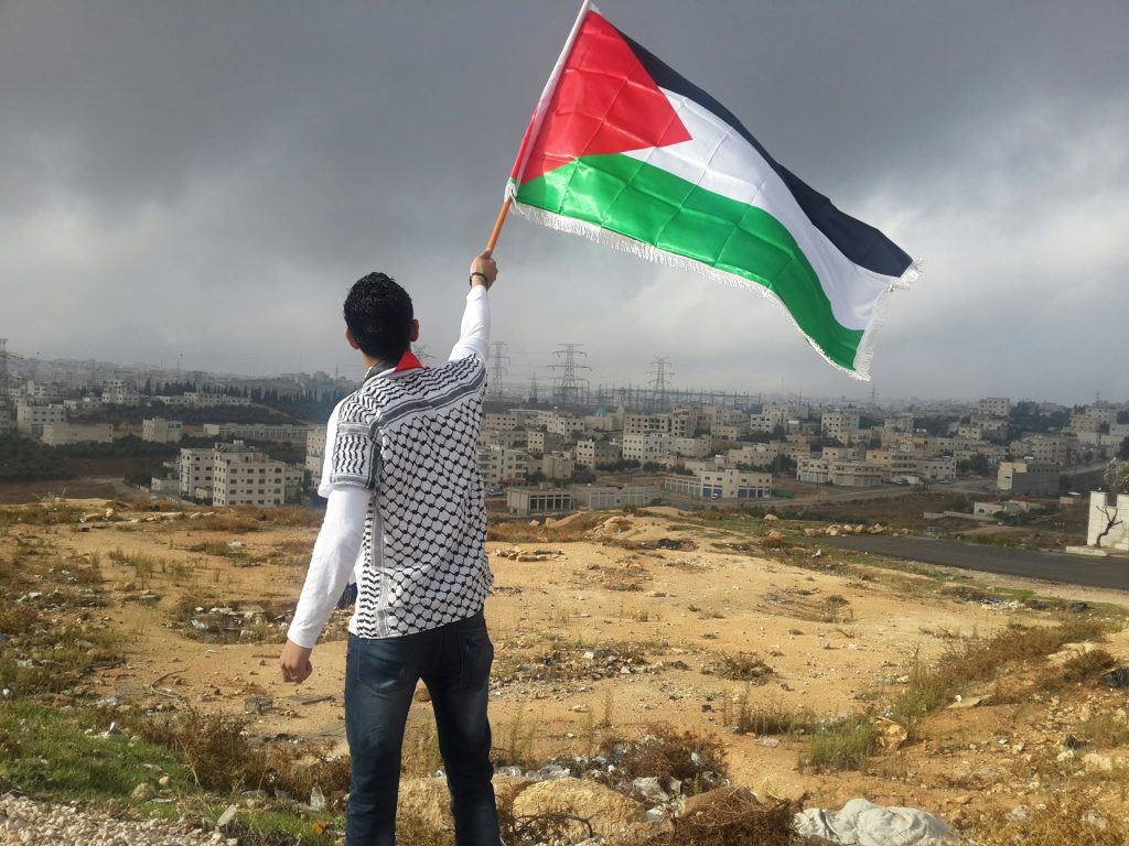 Young man in Gaza waving a Palestinian flag